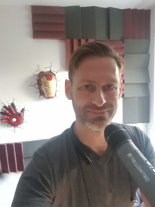 Dirk Primbs vor einer Wand aus Akustikschaumstoff, im Vordergrund ein Yellowtec-Mikrofon.